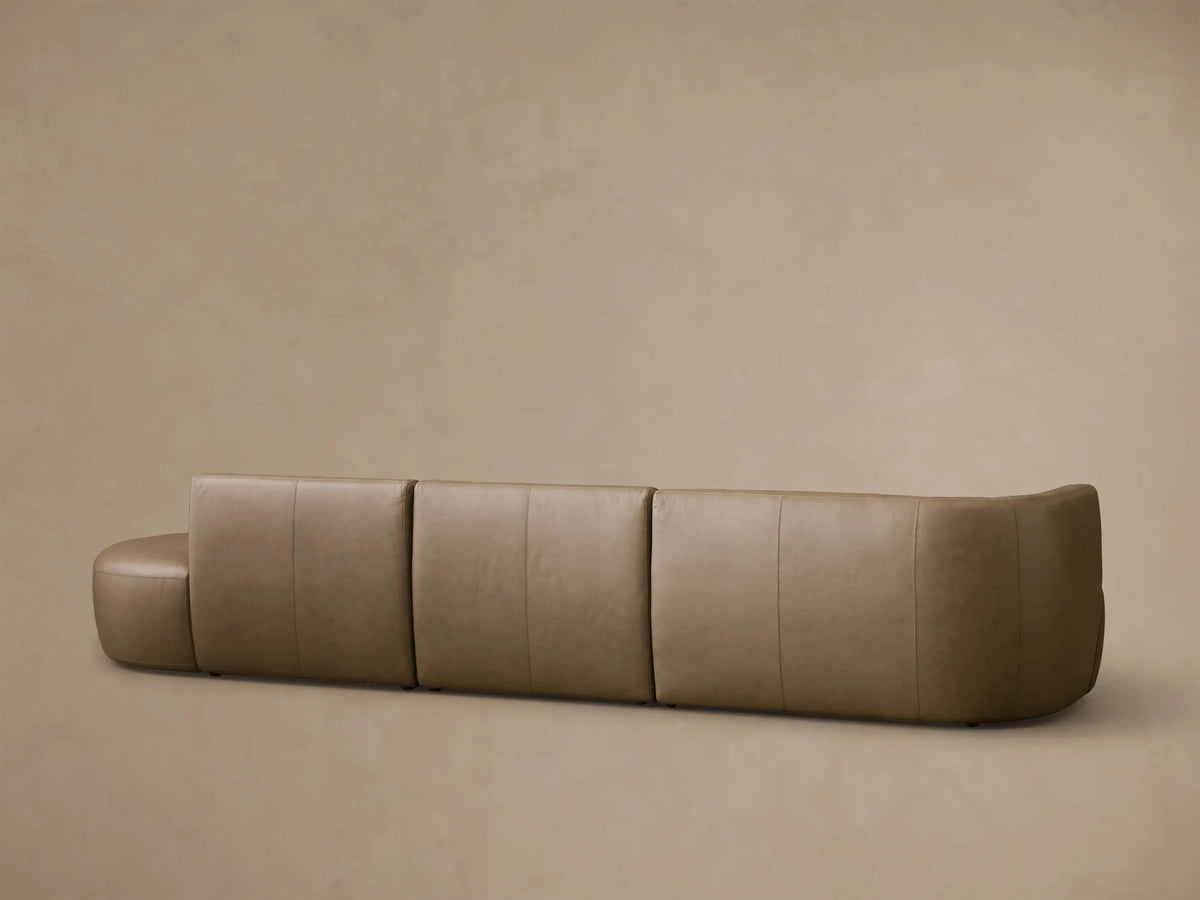 Close-up of the taupe Lovina Leather Three-Piece Bumper Sectional, highlighting the curved corner and stitched seam details.