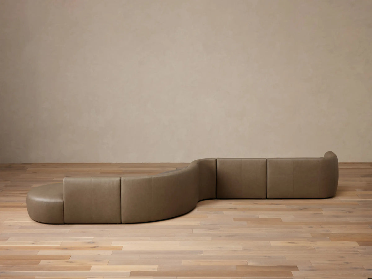 Angled view of the Tan Lovina Leather Five-Piece Sectional, showing its curved, modular design and prominent stitching.
