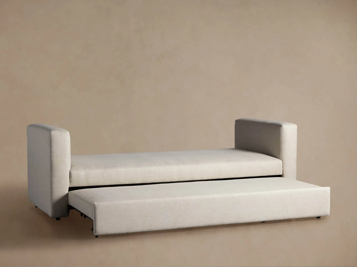 Light beige Remington Trundle Sleeper Daybed with its lower bed partially pulled out, revealing fabric loops and frame.