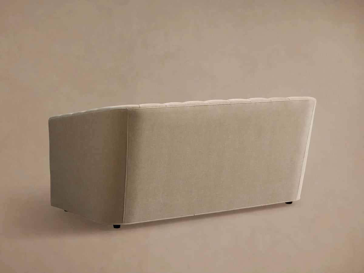 Close-up of the light beige Ellison Channel-Stitched Sofa, showing the curved back and armrest with vertical stitching.
