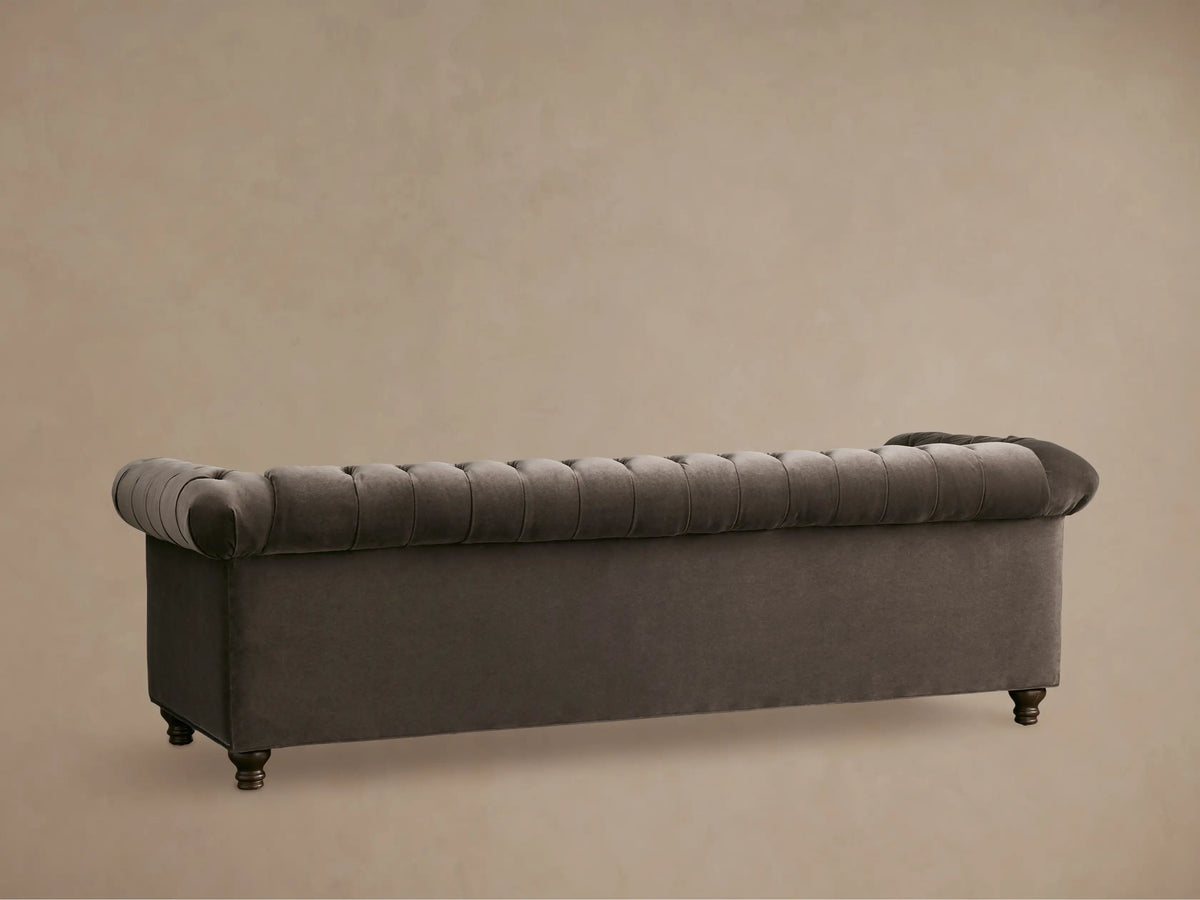 Close-up of a dark brown tufted Berwick Sofa, plush velvet texture on the deeply buttoned seat, back, and rolled arm.