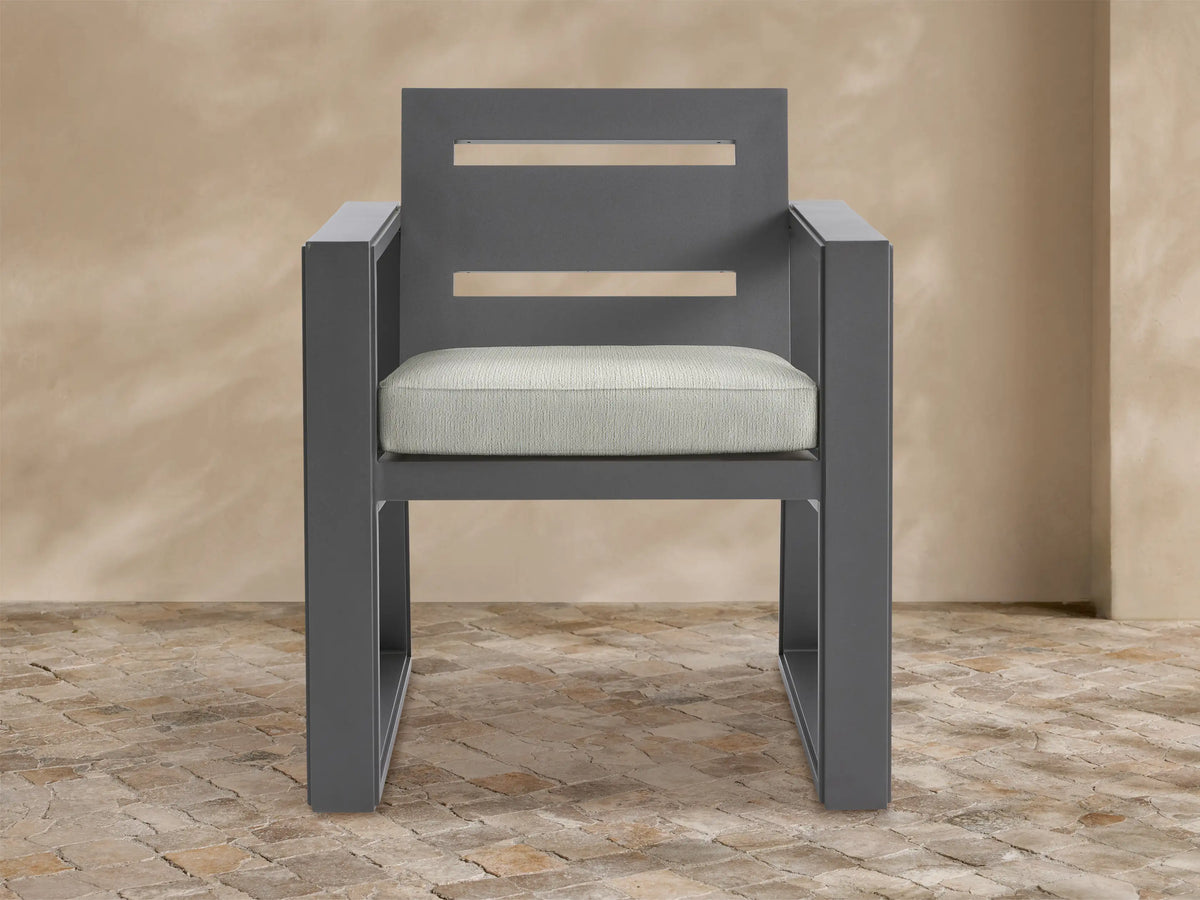 Front view of a dark gray aluminum Canyon Outdoor Dining Arm Chair with a slatted backrest and a light gray seat cushion.