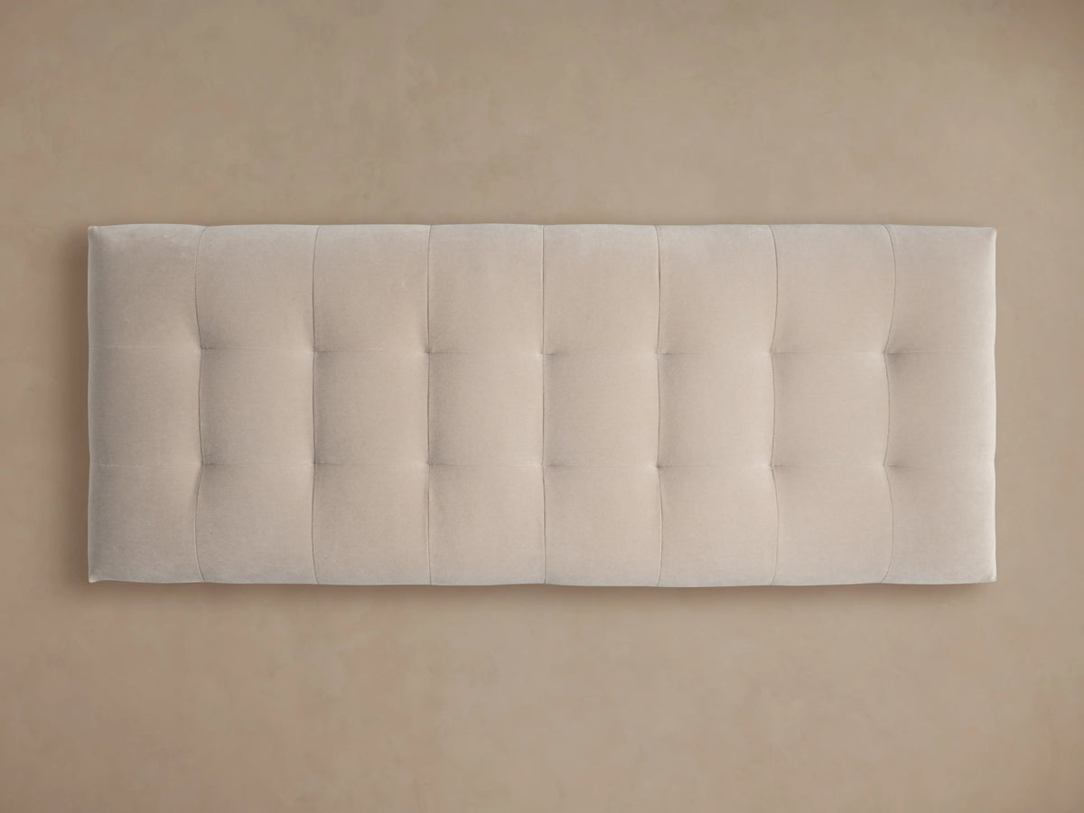 Cameran Bench, a light beige, tufted upholstered bench with a dark base, on a hardwood floor against a neutral wall.