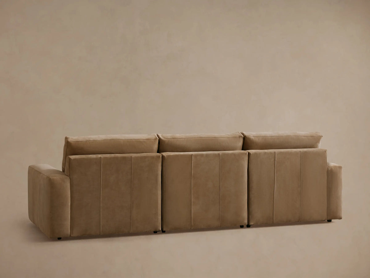 The image shows a close-up of the Kipton Wide Arm Nubuck Leather Sofa in a light brown hue, highlighting the two-button motion control panel embedded in the wide armrest.