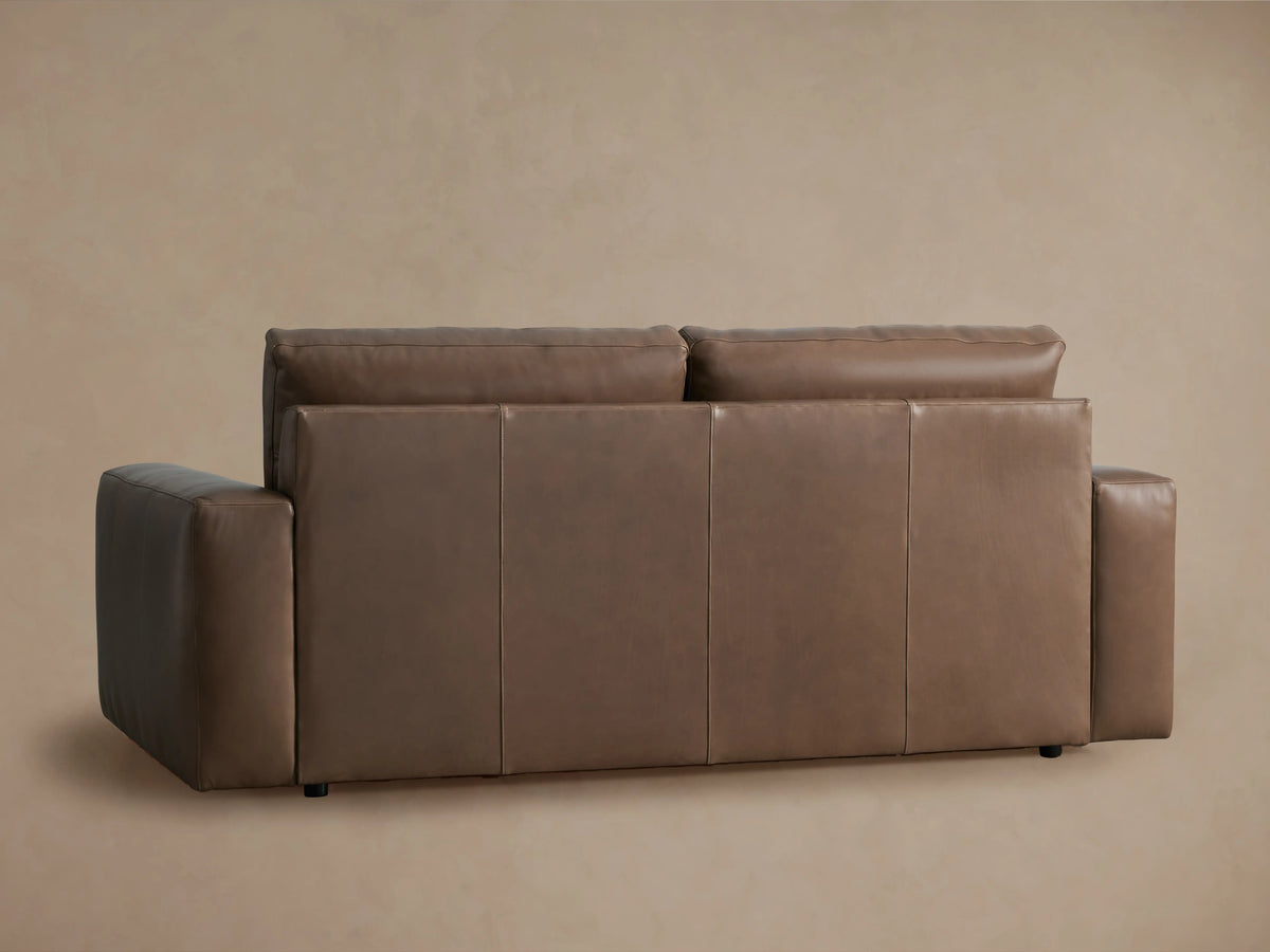 Close-up of the Kipton Wide Arm Leather Sofa in warm brown, showing its wide armrest and seat cushion with precise stitching.