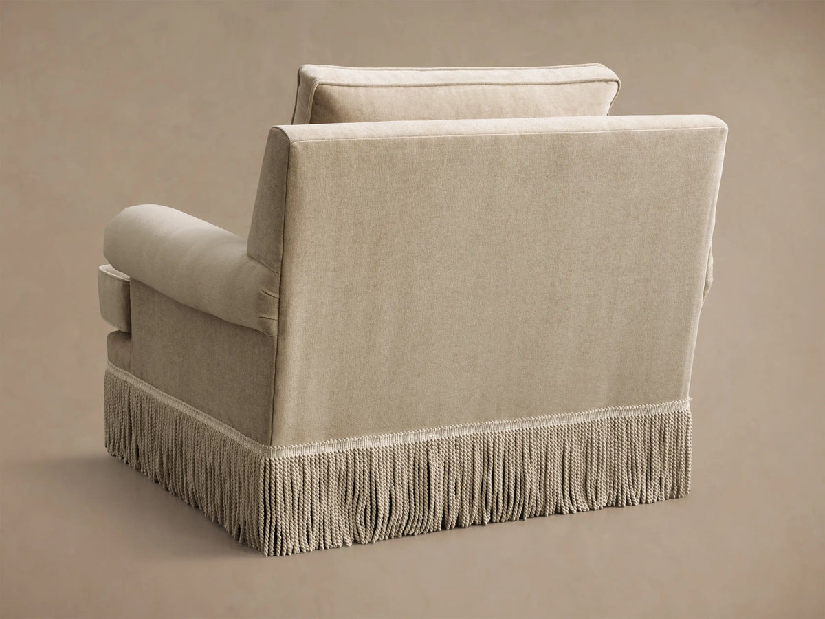 Close-up of the beige McKinley Chair with Fringe, highlighting rolled arms, a piped seat cushion, and a long fringe trim.