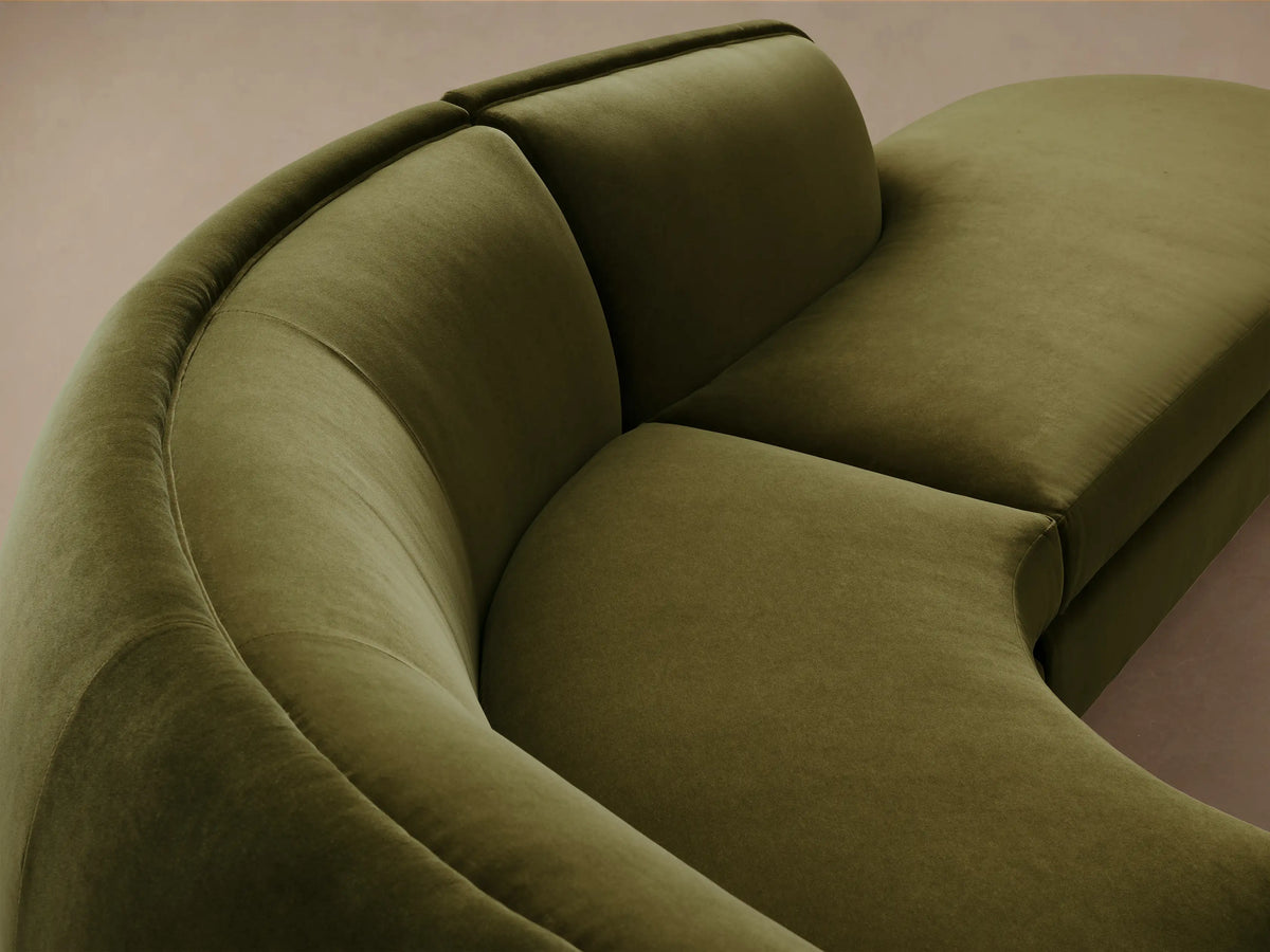 Milana Four-Piece Bumper Sectional in olive green fabric, features a curved design with a corner wedge and armless sections on wood floor.
