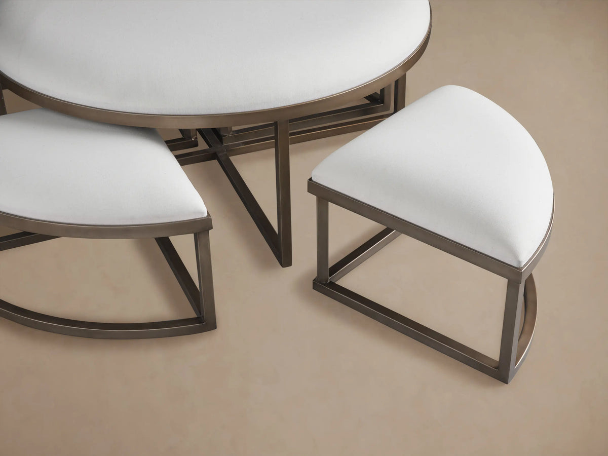 Close-up of Palmer Upholstered Round Nesting Ottomans. White upholstered tops and metallic bronze frames, partially nested.