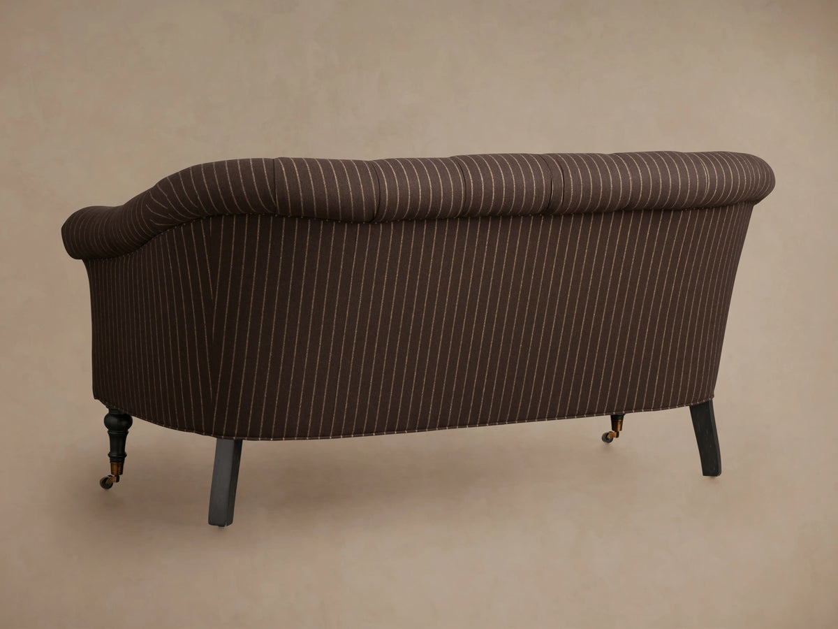 Tangier Settee with brown fabric and white pinstripes, tufted backrest, rolled arm, and dark wooden legs on a neutral background.