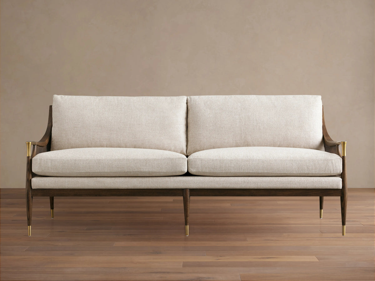 Fisher Cane Back Sofa with beige cushions. Crafted from red oak wood in mocha finish, features cane detailing and slender legs.