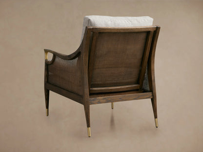 Cane back chair with mocha-finished oak frame, gold metal arm accents, gray cushioned seat, and textured fabric upholstery.