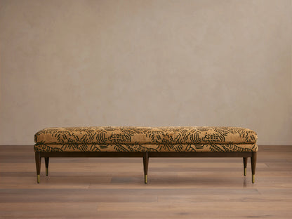 Fisher Bench with mocha-finished red oak frame, camel-colored cushion with abstract black pattern, set on a wooden floor.