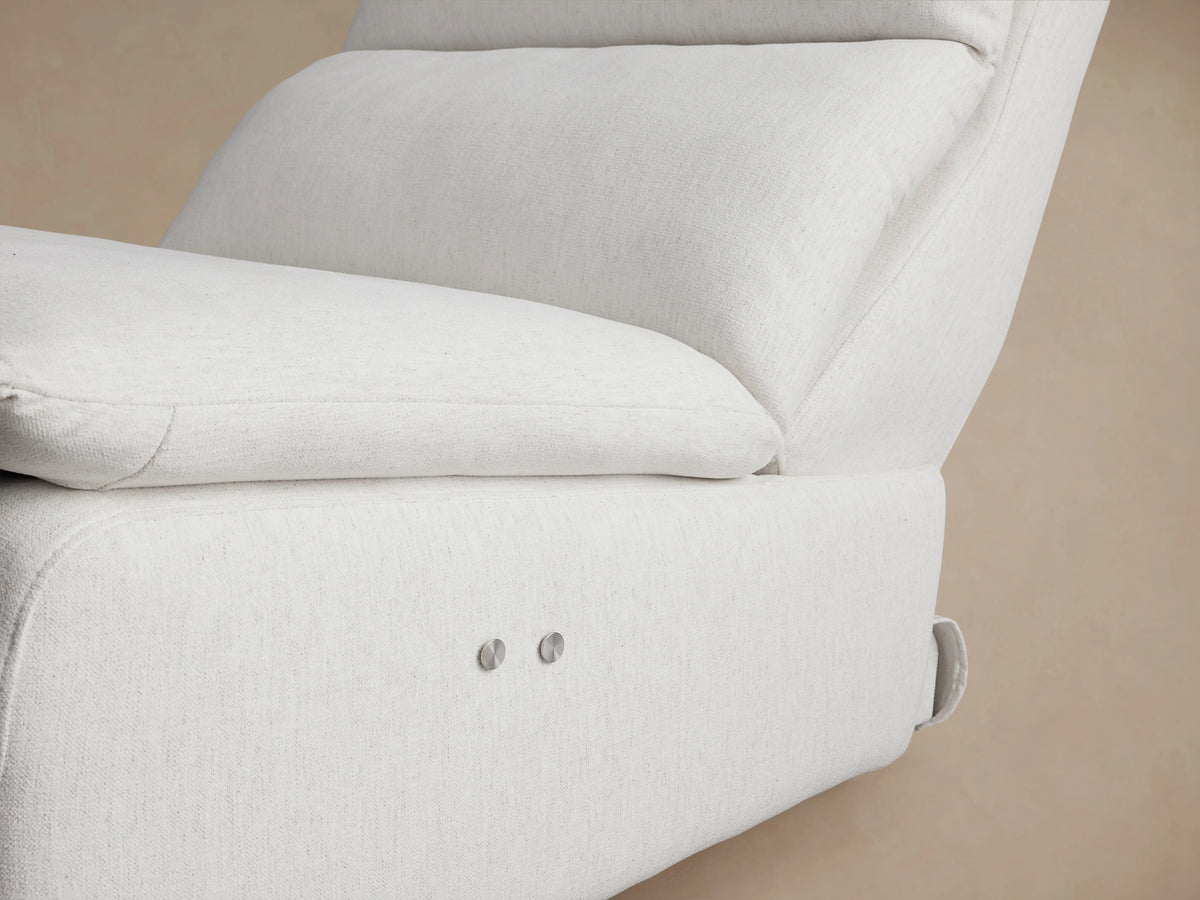 Rowland Tailored 34" Armless Motion Recliner, light cream textured fabric, front view on wood floor against tan wall.