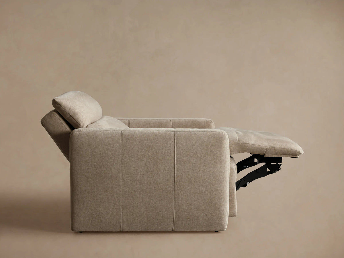 Angled close-up of a light beige Rowland Tailored High-Back Motion Recliner, showing its textured fabric, armrest, and tailored seams.