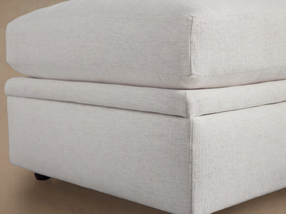 Kipton Storage Ottoman in light beige fabric with open lid, revealing spacious interior. Set on wooden floor against neutral background.