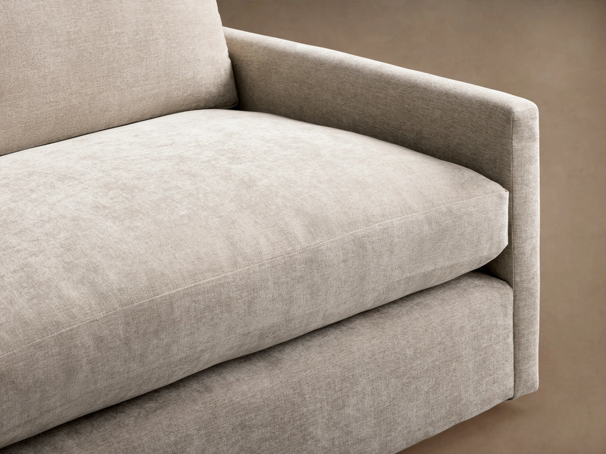 Kipton Sofa in a light beige fabric, featuring a modern, rectangular design with cushioned seats and backrests, set on a wooden floor.