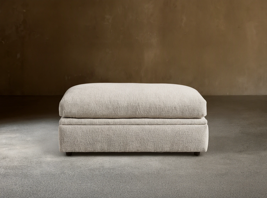 Light beige textured Kipton Storage Ottoman, rectangular with soft, rounded cushion top, on wood floor.