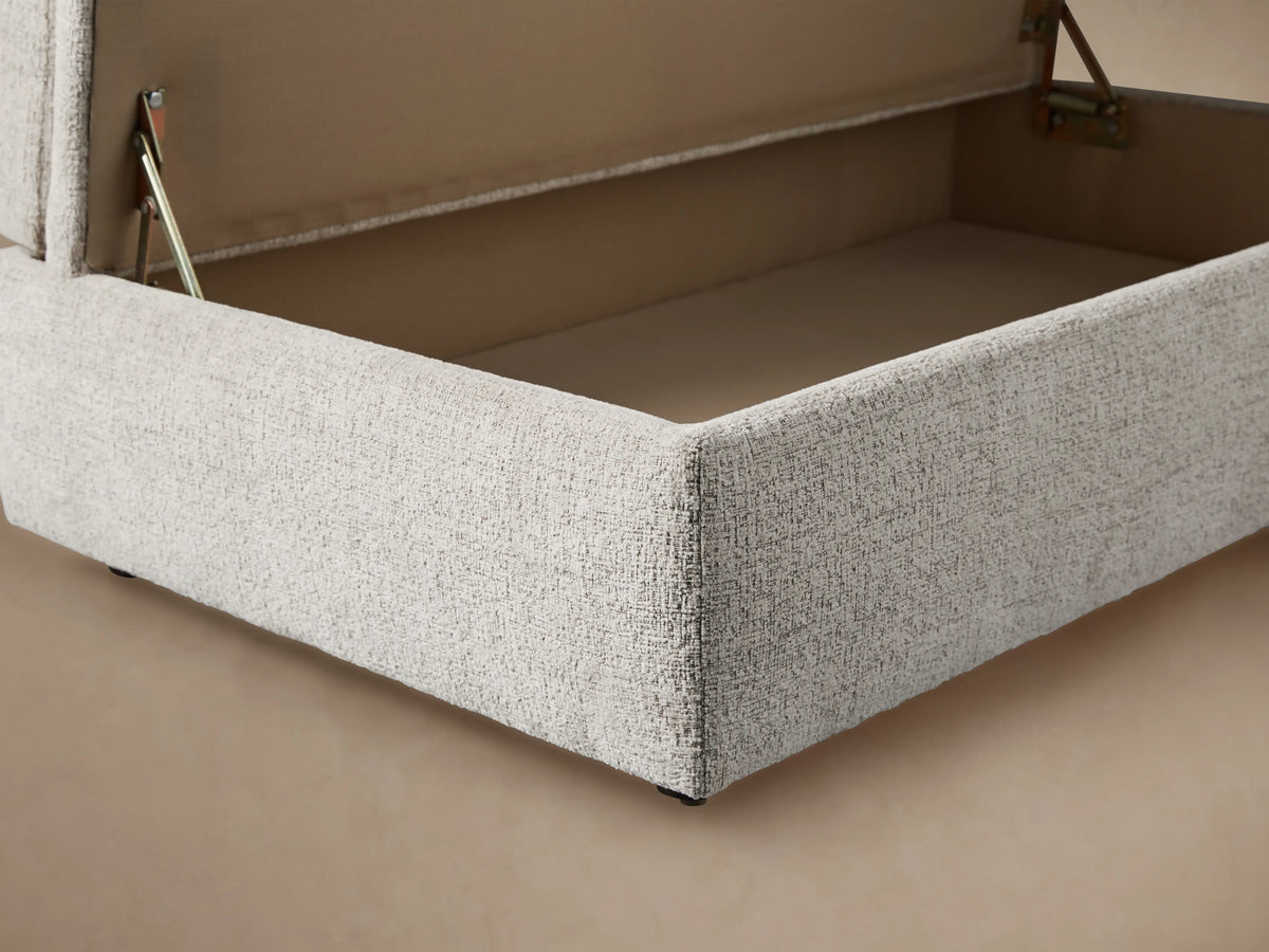Light cream Kipton Storage Ottoman, rectangular with a plush, domed top cushion and textured fabric, in an angled view.