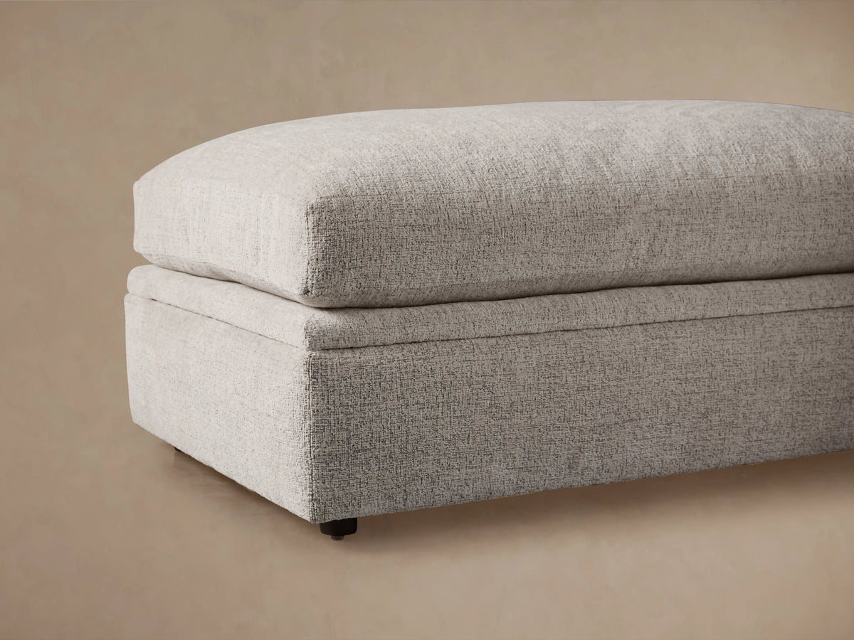 Light gray Kipton Storage Ottoman, lid open revealing empty beige storage compartment, metal hinges visible.