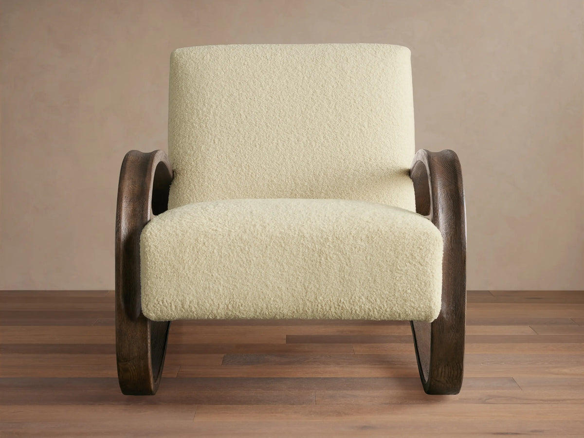 Allora Chair with curved red oak wood frame in Mocha finish, beige textured cushions, on wooden floor, against neutral wall.