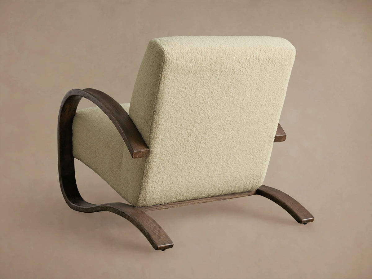 Allora Chair close-up showing a curved, mocha-finished red oak armrest, light beige textured fabric backrest and seat cushion.
