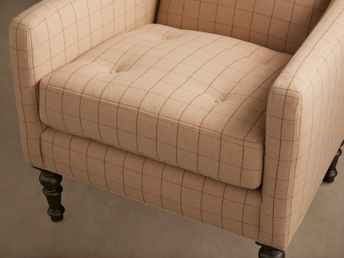 Fenwick Chair in beige fabric with a subtle grid pattern, featuring a cushioned seat and elegantly turned wooden legs on a hardwood floor.