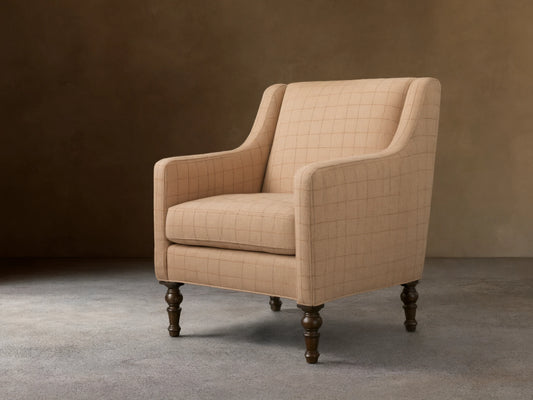 Tan plaid Fenwick Chair with a high backrest, cushioned seat, and curved arms on dark turned wooden legs, on hardwood floor.