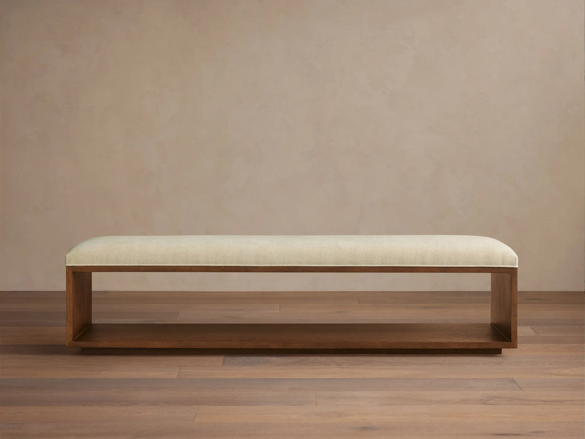 Taya Bench: Rectangular bench with light cream upholstered seat and open mocha brown wood frame base, viewed head-on.