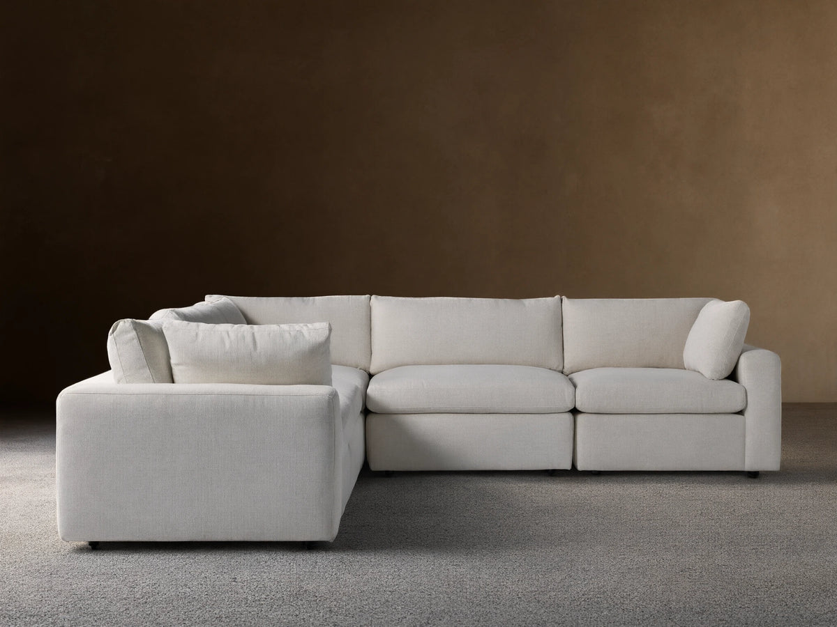 Beale Five-Piece Corner Sectional in off-white fabric, L-shaped with plush cushions, on wooden floor against a beige wall.