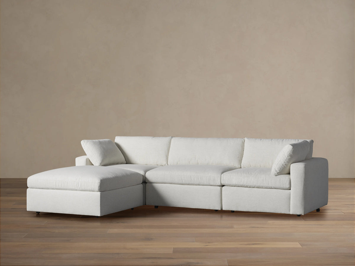 Light gray fabric Beale Four-Piece Sectional with plush cushions, a left chaise, on wood floor against a neutral wall.