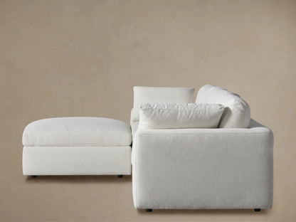 Close-up of the Beale Sectional's light gray woven fabric, featuring a plump back cushion and rounded top edge of the base.
