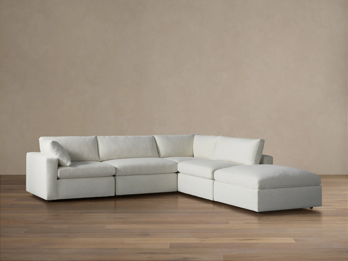 Beale Five Piece Sectional sofa, modular, light cream fabric, with a right chaise lounge, on wood floor, tan wall background.