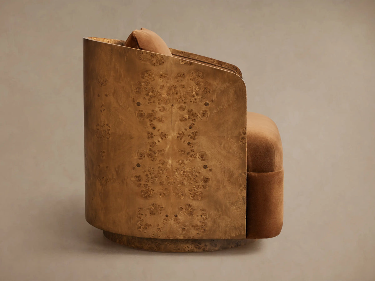 Side view of Tilda Swivel Chair with curved light brown burl wood shell and warm caramel velvet seat and back pillow.