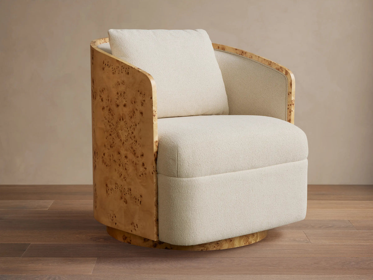 Angled Tilda Swivel Chair, cream boucle upholstery, curved burl wood frame & base, with a matching back cushion.