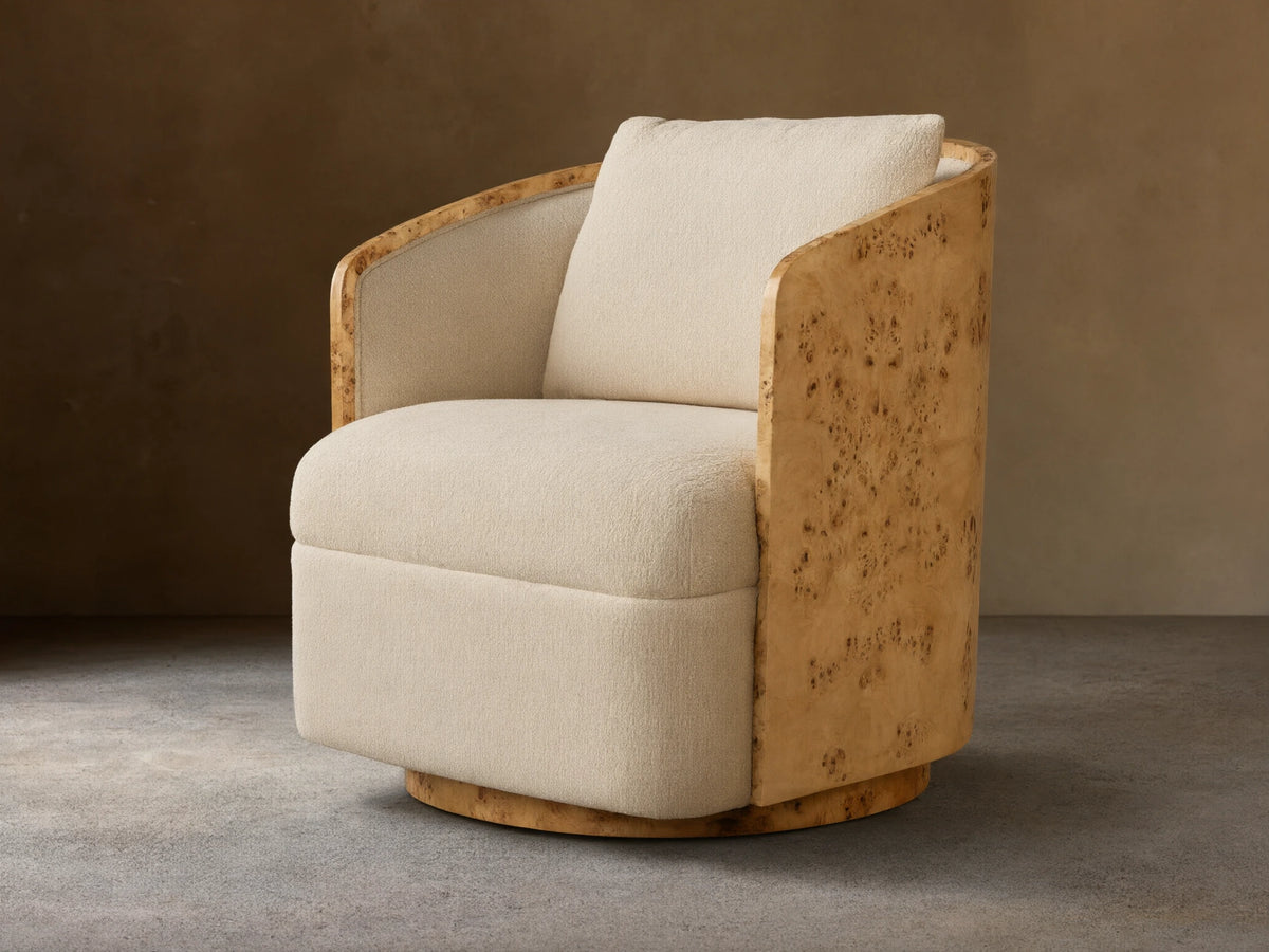 Angled Tilda Swivel Chair, cream boucle upholstery, curved burl wood frame & base, with a matching back cushion.