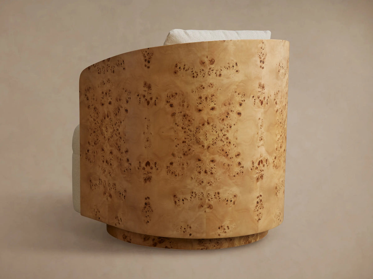 Side view of Tilda Swivel Chair with curved light brown burl wood back and subtle mottled grain, light upholstered cushion.