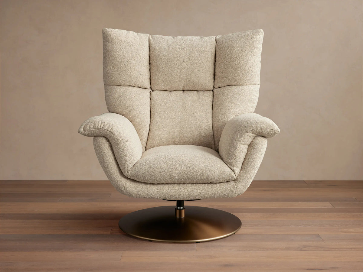 Deacon Swivel Recliner in beige fabric, with high cushioned backrest, curved armrests, and a bronze swivel base on wooden floor.