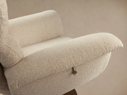 Deacon Swivel Recliner in soft beige fabric, wide padded arms, high backrest, on a bronze-toned swivel base, on wood floor.