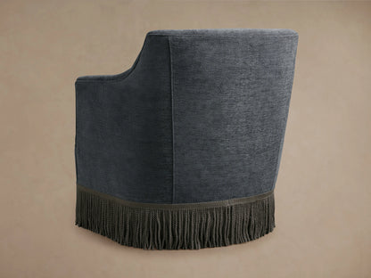 Savannah Swivel Chair in dark gray fabric with fringe detailing at the base, featuring a curved backrest and armrest design.