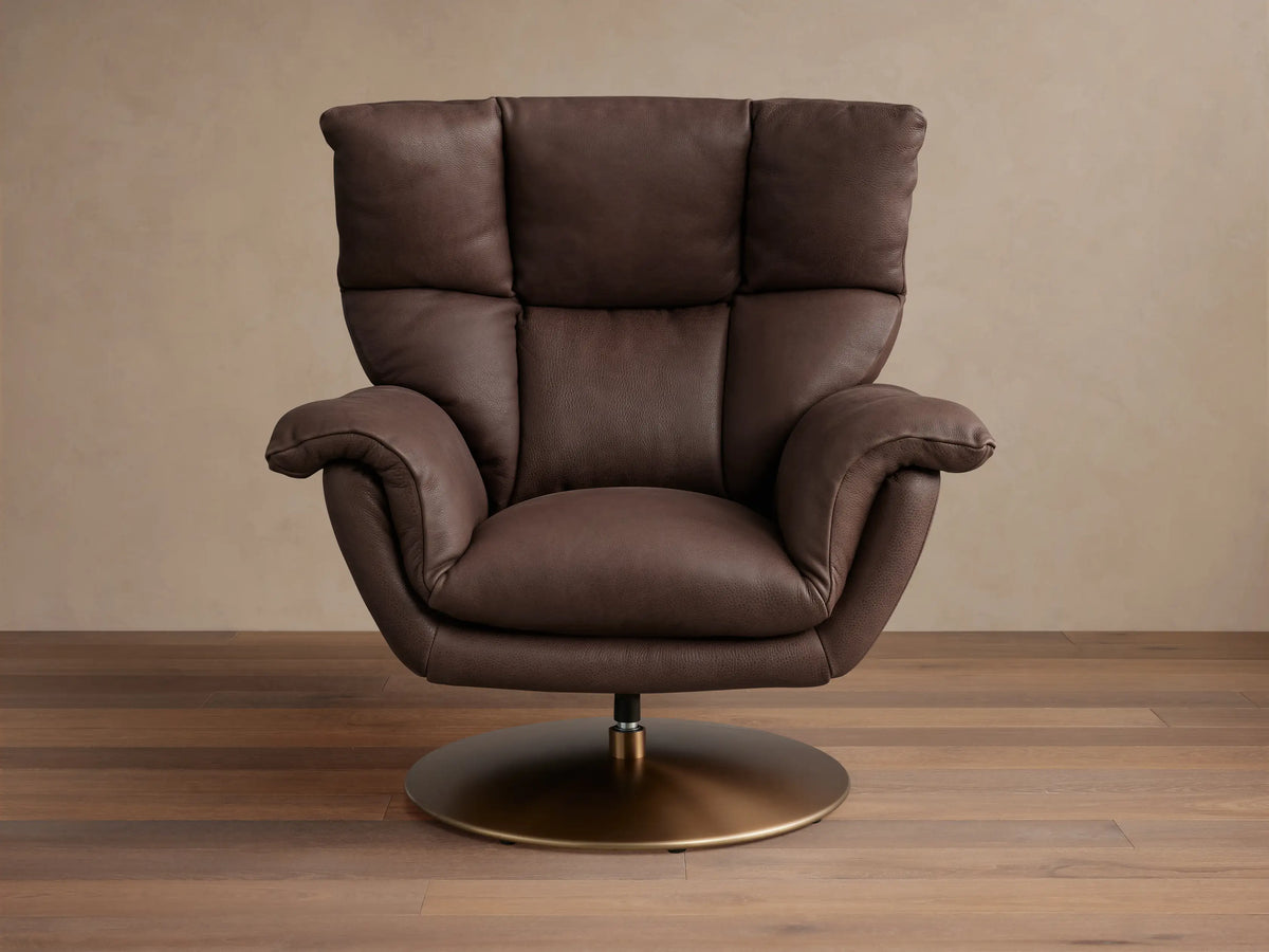 Deacon Leather Swivel Recliner in brown leather with padded armrests, tall backrest, and a brass swivel base, set on wooden floor.