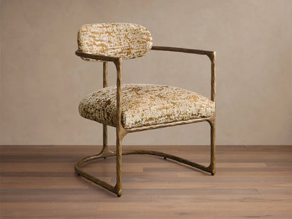Front view of the Nataly Chair with gold and green patterned upholstery, featuring an exposed textured light brass frame.