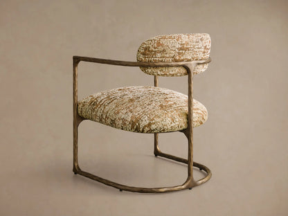 Front 3/4 view of the Nataly Chair, featuring a hammered light brass frame and cream upholstery with a mottled brown and green pattern.
