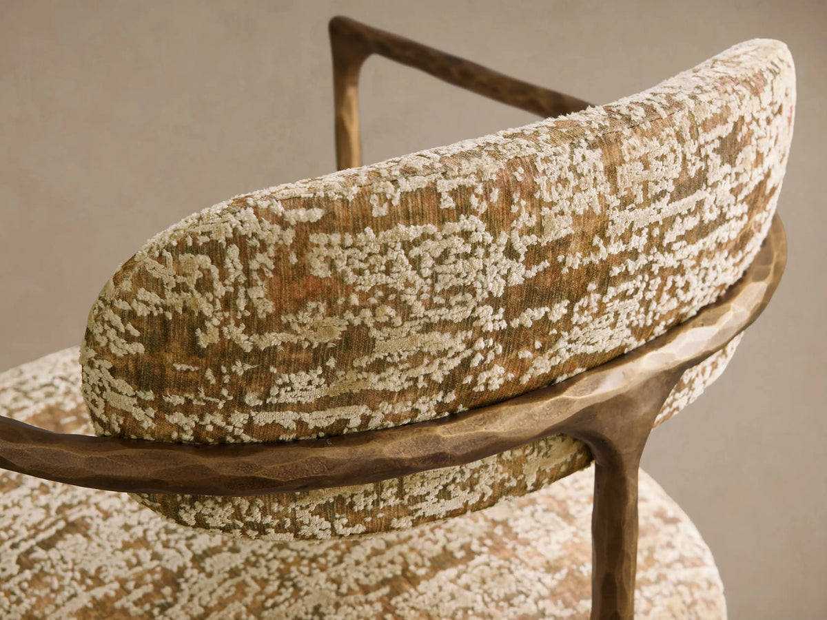 Front view of the Nataly Chair with gold and green patterned upholstery, featuring an exposed textured light brass frame.