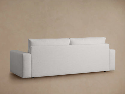 Kipton Wide Arm Sofa in light gray fabric, viewed from the back. Features wide armrests and minimalist design against a beige background.