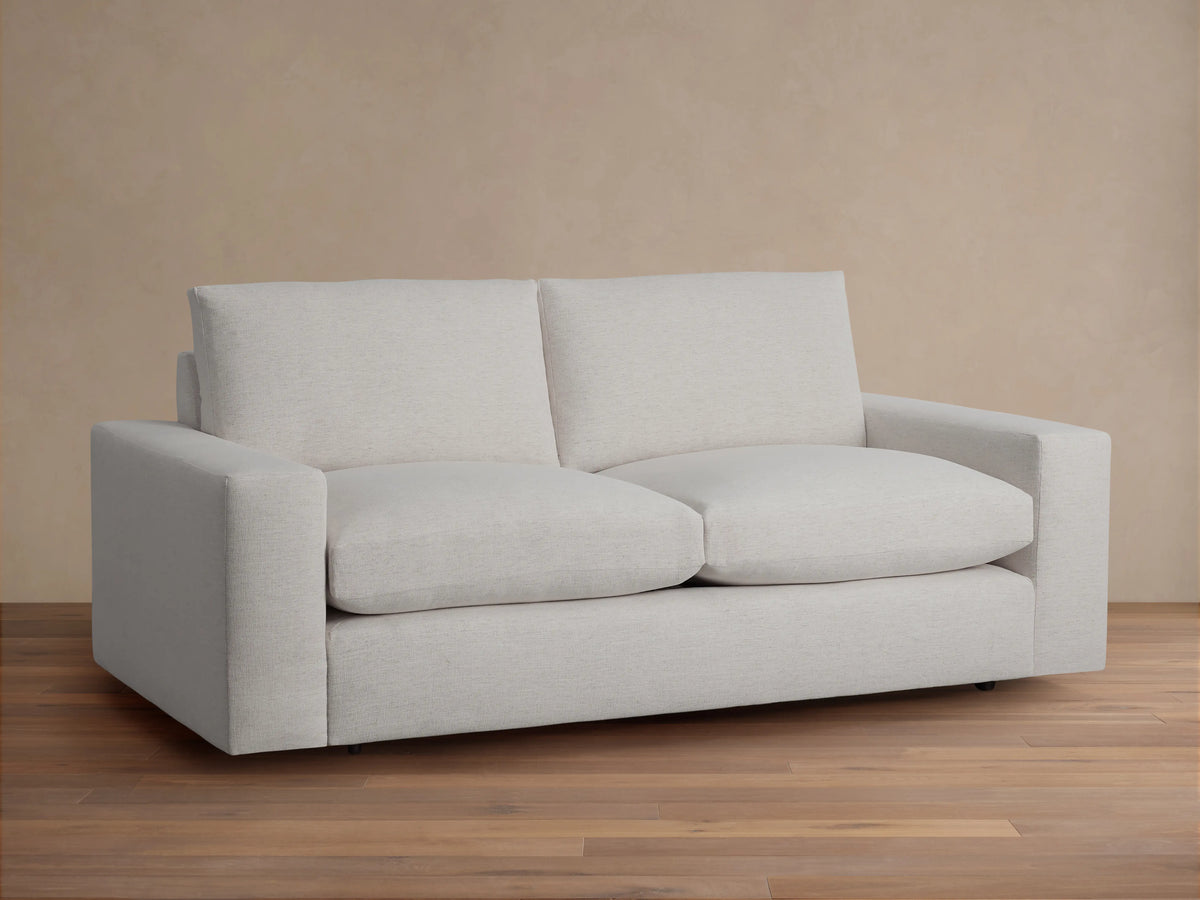 Wide arm of the Kipton sofa in light neutral fabric with a smooth texture. Simple, sleek design on a beige background.