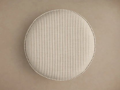 Top-down view of the round beige and white striped upholstered Mimi Ottoman, featuring prominent piping around the edge.