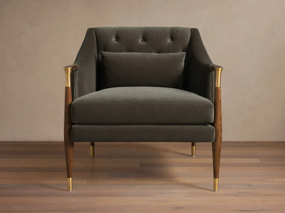 Front view of a dark olive green Fisher Club Chair with a tufted back, lumbar pillow, exposed wood arms with brass details, and tapered brass-capped legs.