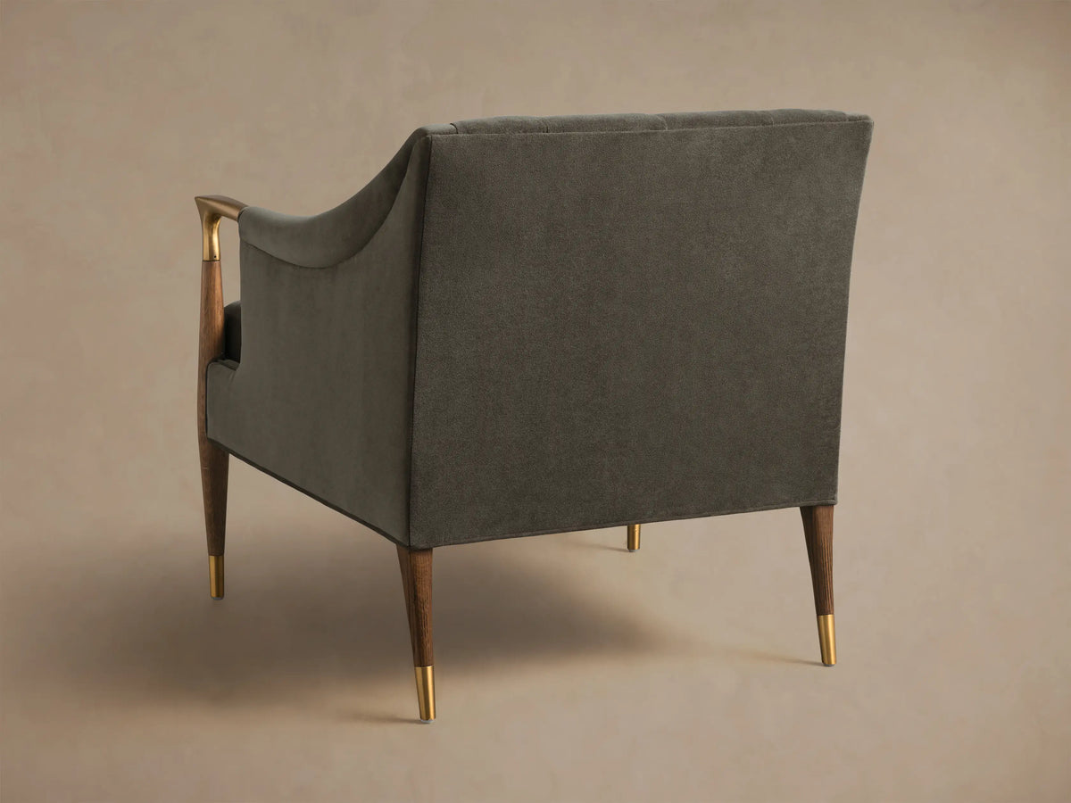 Rear-side view of the dark gray upholstered Fisher Club Chair, showing tapered wooden legs with brass caps and a wooden arm with brass detail.