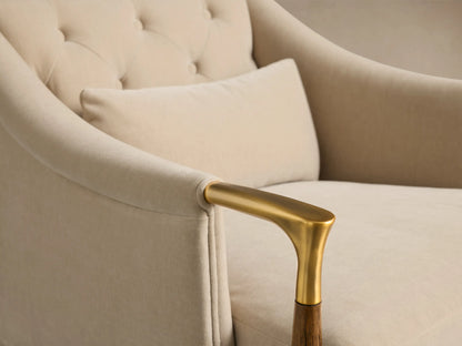Detail view of the beige Fisher Club Chair, showing a tufted back, matching lumbar pillow, and a brass armrest with wood accent.
