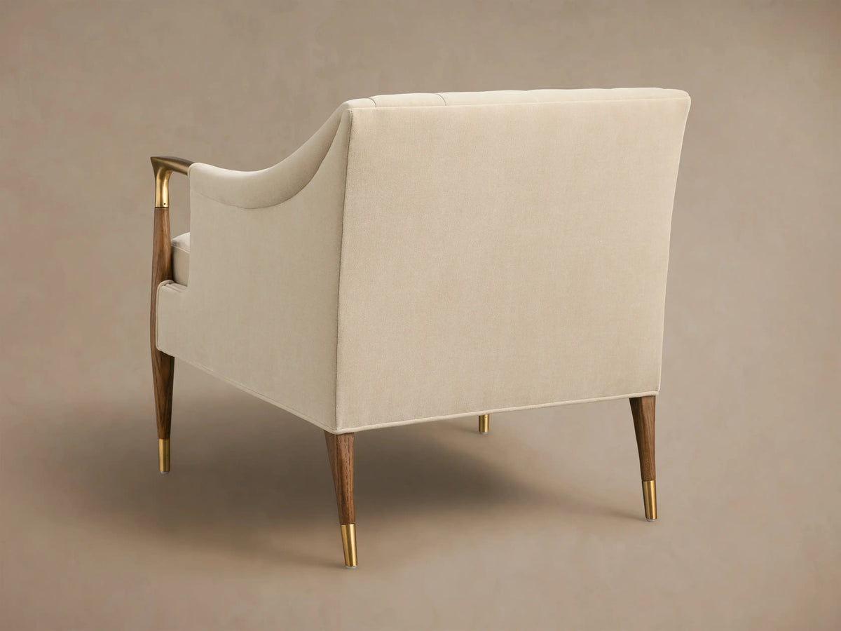 Front view of cream Fisher Club Chair with tufted back, dark wood arms and legs with brass accents, includes matching lumbar pillow.